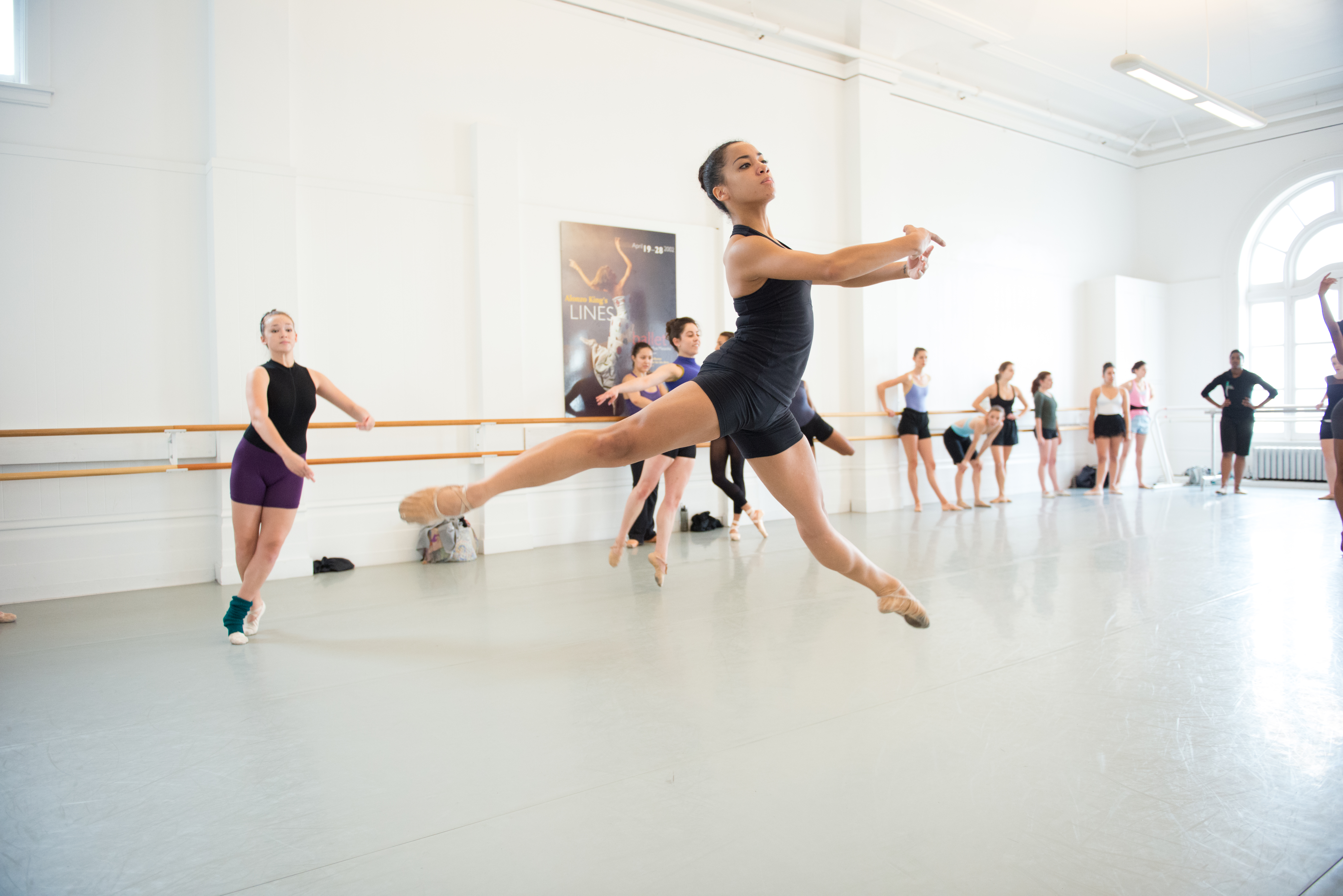 A BFA student mid-sissone in a ballet class