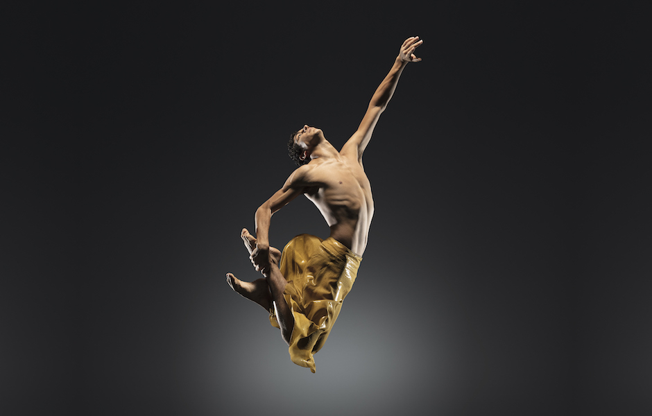 Company Dancer Alvaro Montelongo jumping in a gold skirt