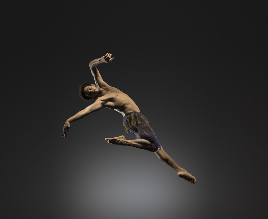 LINES Ballet company artist Michael Montgomery suspended in a jump in the air in front of greyish white background