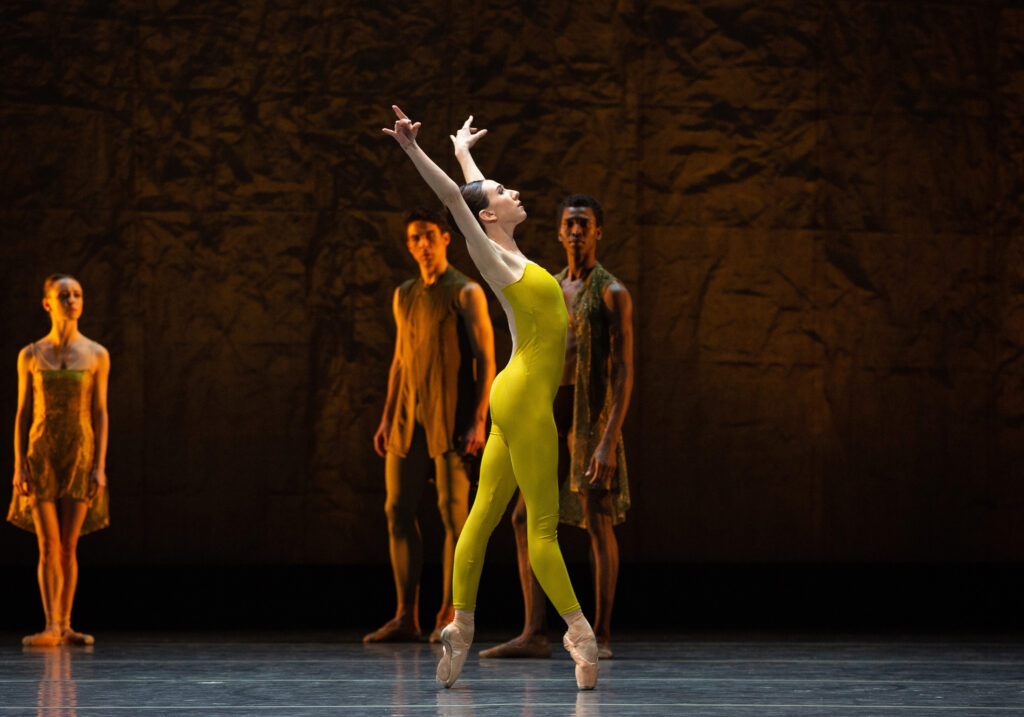 Isabella Boylston en pointe performing in Alonzo King's "Single Eye". Other ABT dancers watch her in the background on stage.
