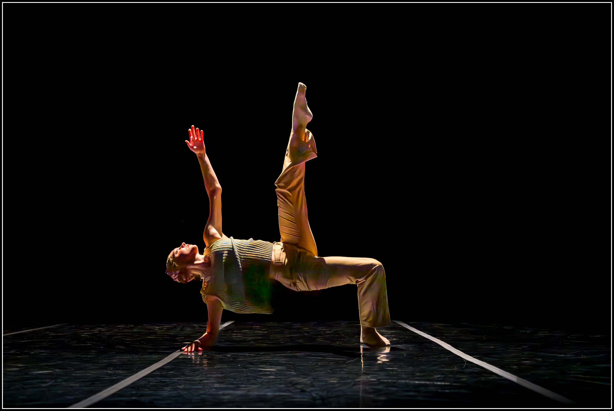 BFA at Dominican student Bailey Storm performing on stage; Bailey is dancing floorwork with one leg extended up into the air; BFA Senior Showcase imagery