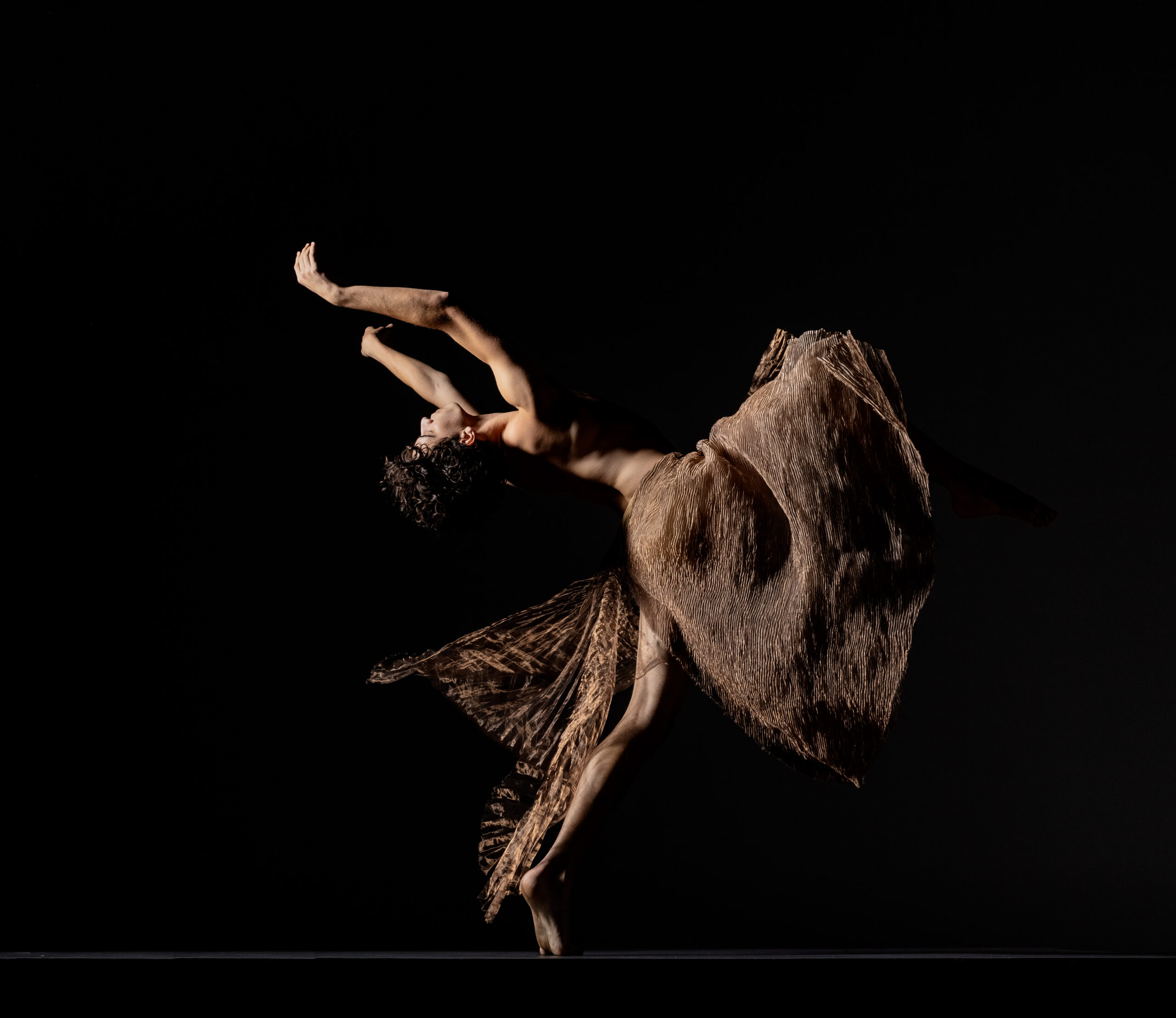 LINES Ballet company dancer Maël Amatou dancing, wearing shimmery brown/golden fabric