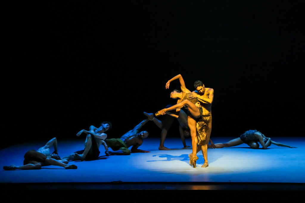 LINES Ballet company dancers Adji Cissoko and Shuaib Elhassan partnering on stage during a performance of Alonzo King's "Deep River" while other company dancers perform floorwork in the background