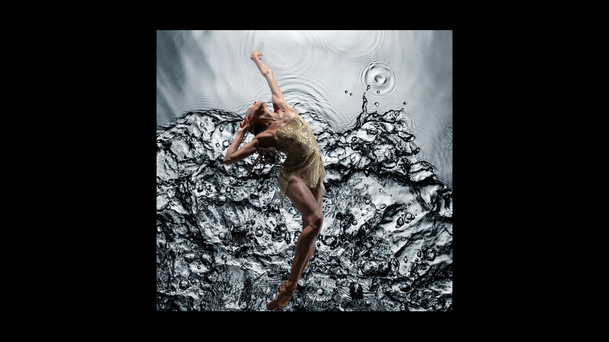 Dancer Adji Cissoko dancing wearing a shiny gold costume in front of a rippling surface of water