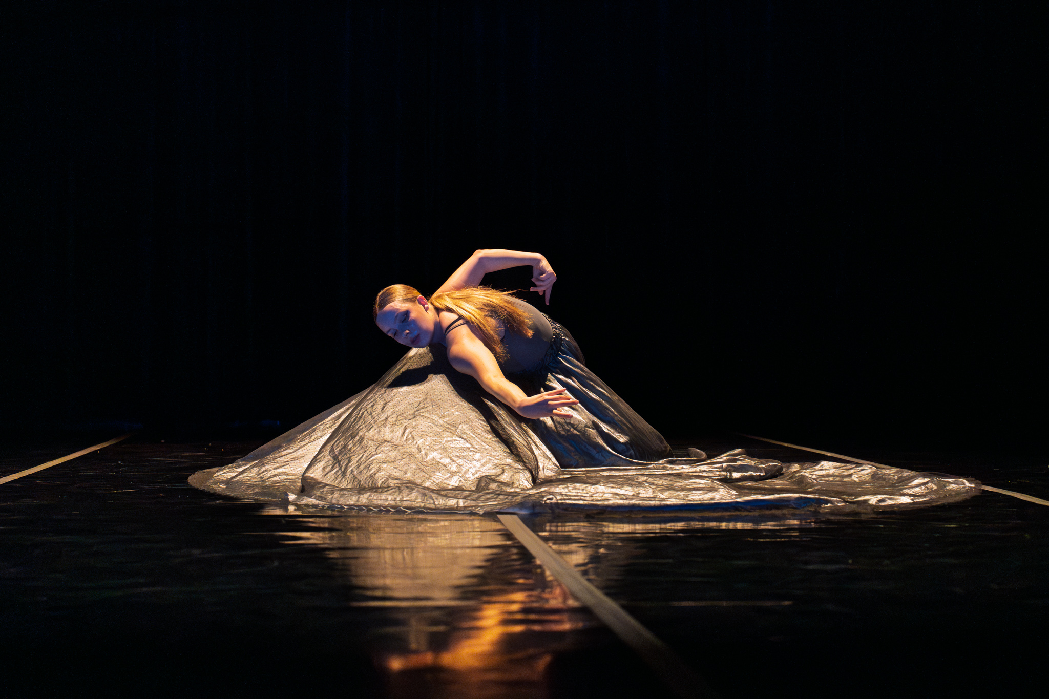 BFA dancer building a shape on bended knee with a voluminous grey shiny skirt