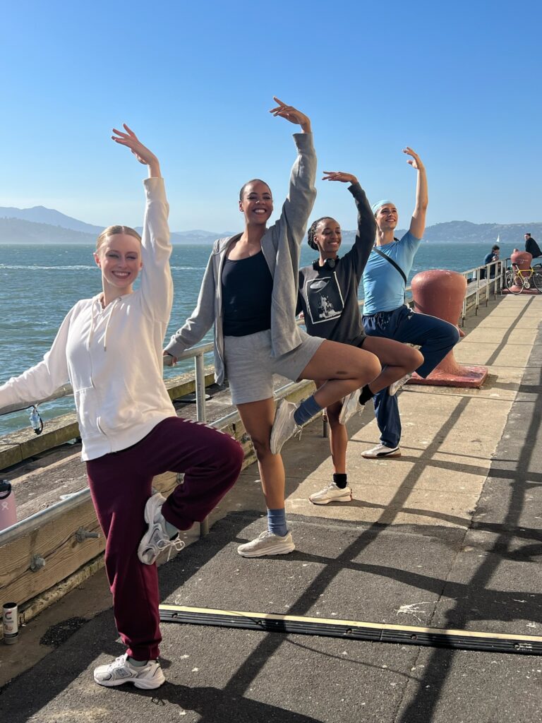 Summer program students in ballet pose with the San Francisco Bay behind them