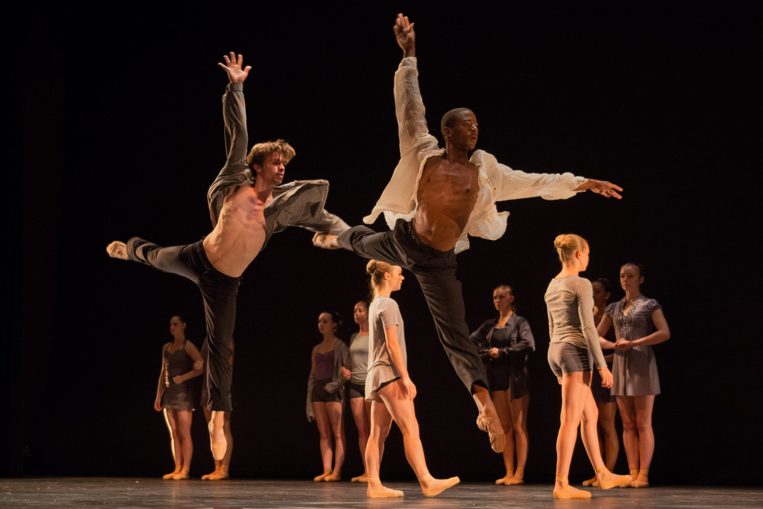 Two summer program students jumping with group of dancers behind them