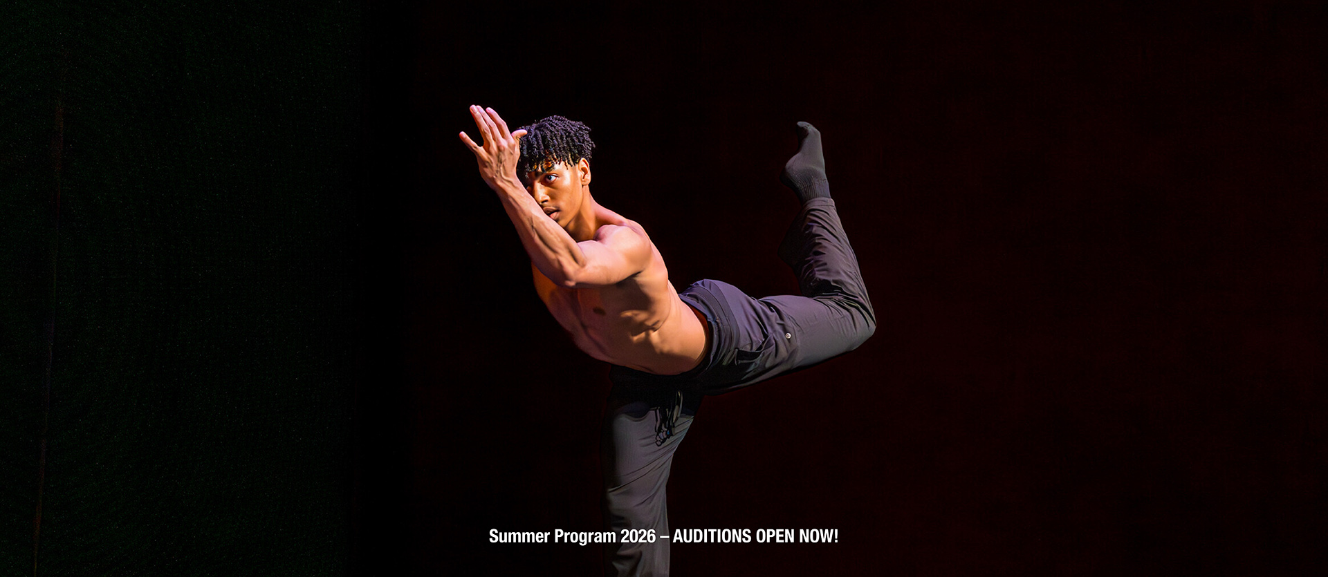 Summer Program student performs onstage wearing black pants and socks, appearing to run in slow-motion