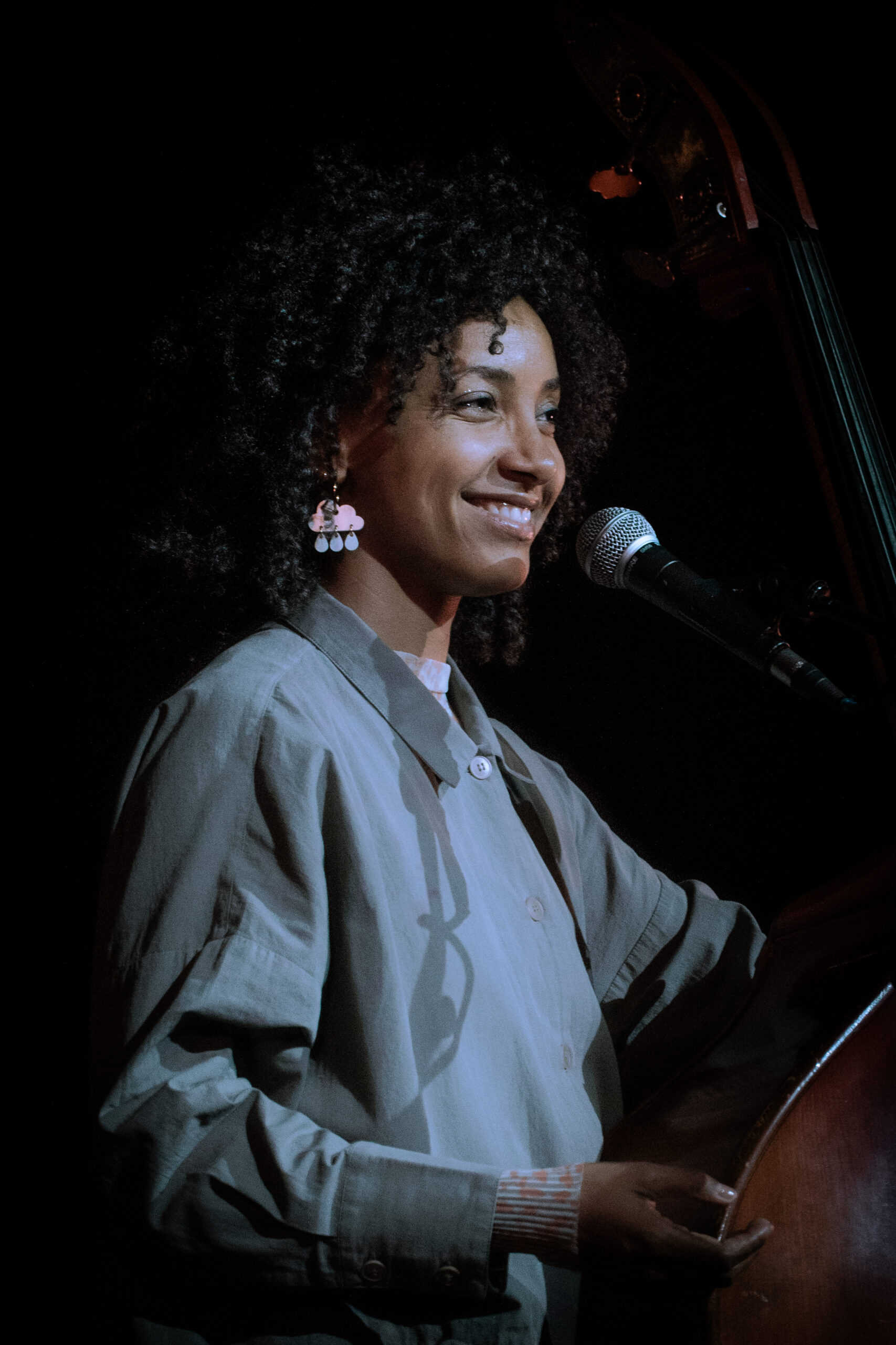 esperana spalding smiles at a microphone with her bass