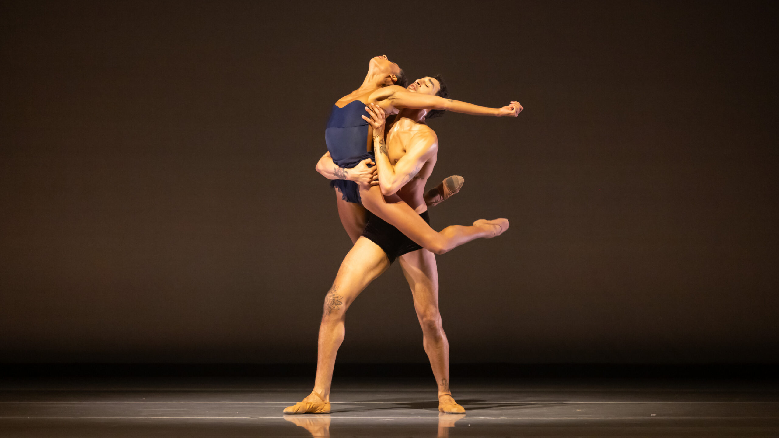 Company Dancer Adji Cissoko supported from behind by Company Dancer Shuaib Elhassan onstage in LEGACY.