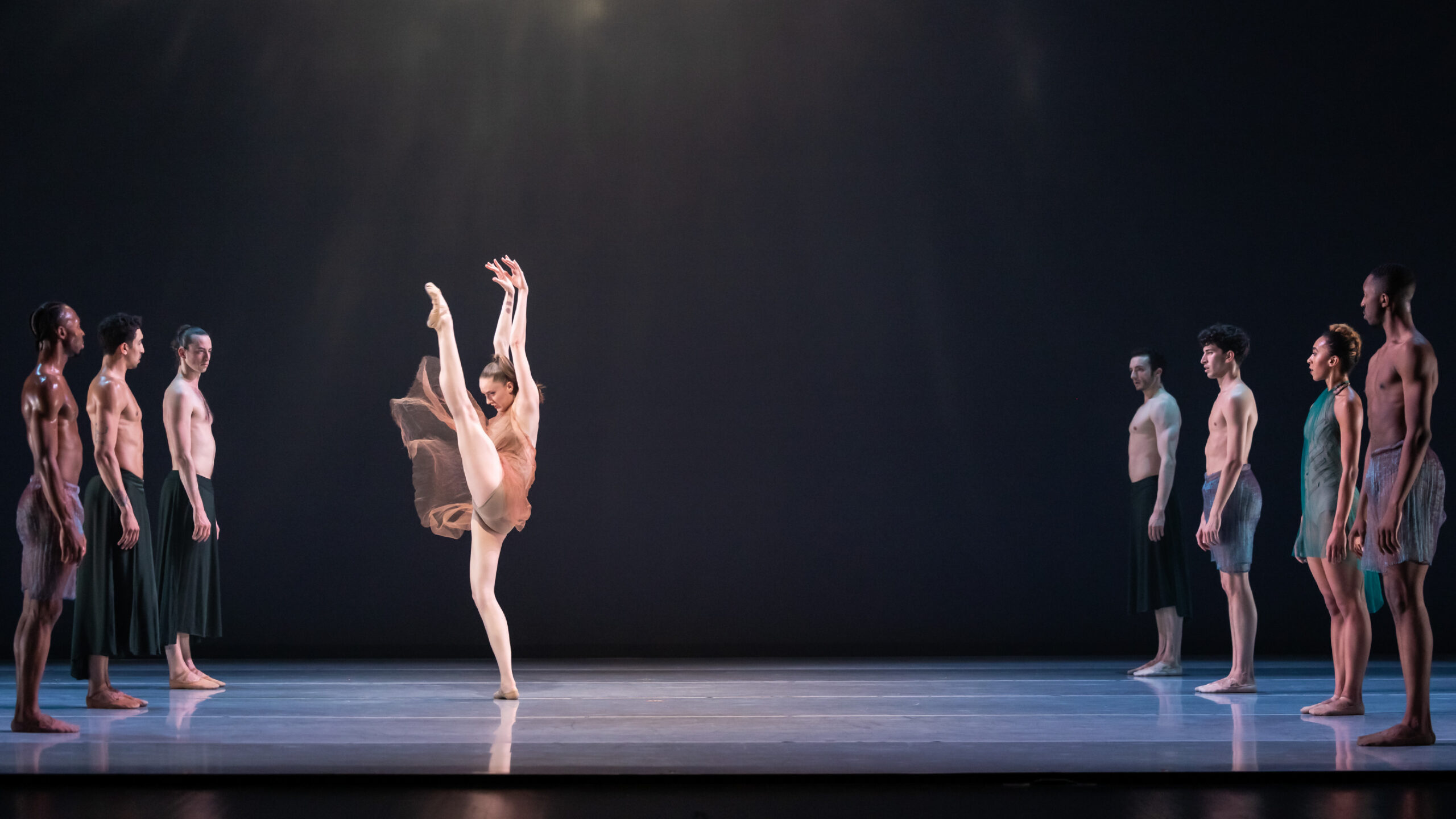 Dancer Tatum Quiñónez in 'Ode to Alice Coltrane' onstage with LINES Company. She is wearing a peach flowy dress and is poised on one leg, the other up to the sky.