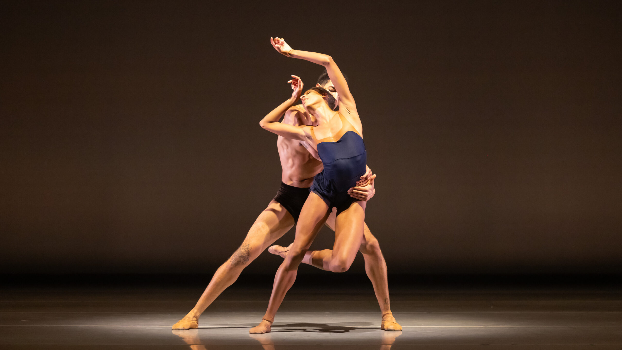 Company dancers Adji Cissoko and Shuaib Elhassan counterbalance one another onstage.